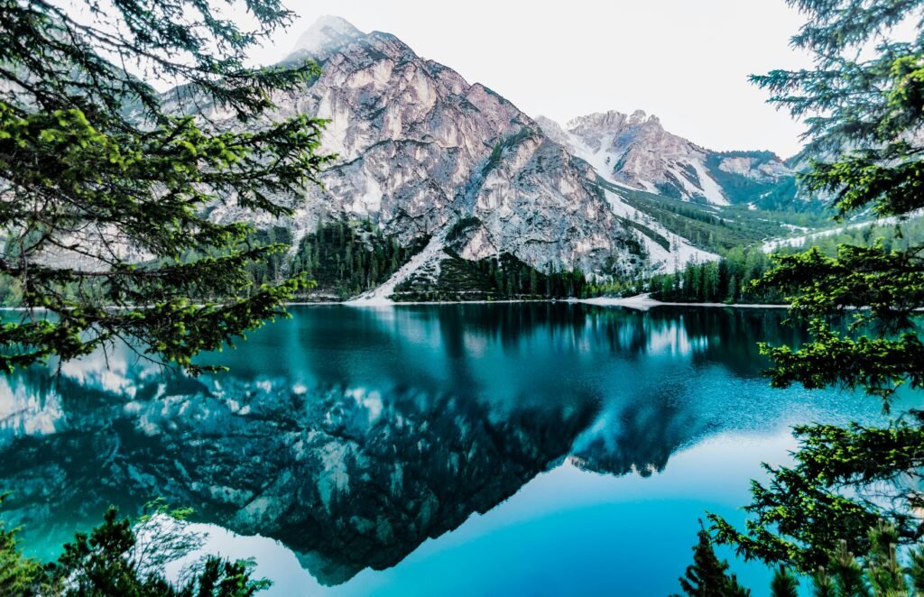 Serene mountain lake with stunning reflections in Braies, Italy, surrounded by trees.